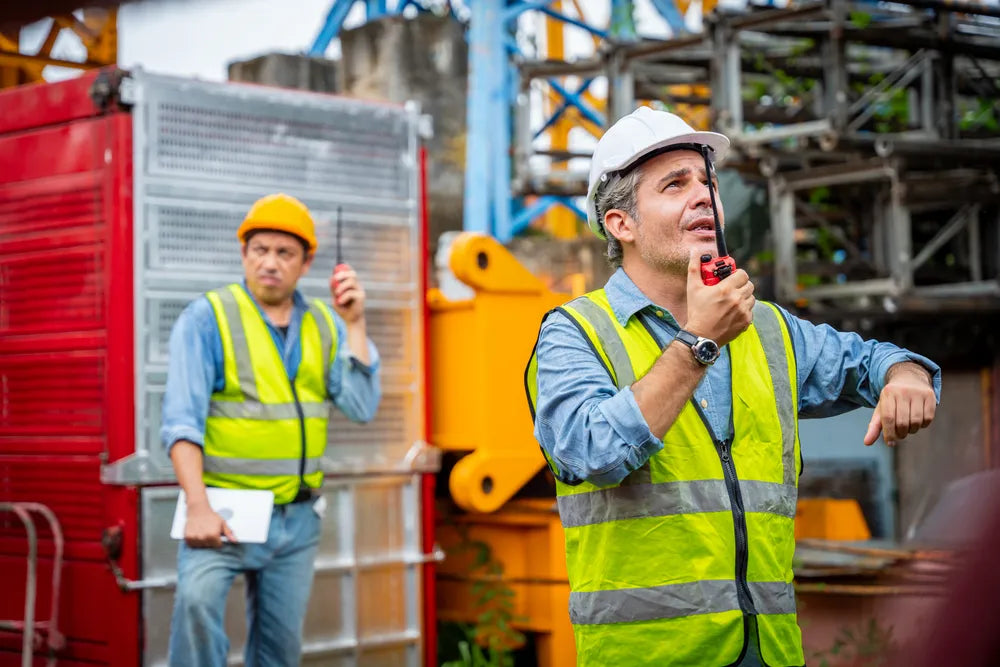 Fotografía de dos Ingenieros comunicándose con radios para uso rudo en una industria de construcción