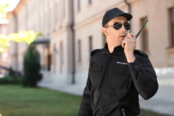 Foto a un joven de uniforme negro usando uno de los radios de comunicación para seguridad privada de COMREGIO
