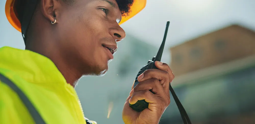 Foto de un Joven ingeniero que trabaja en construcción usando uno de los radios para uso rudo de COMREGIO