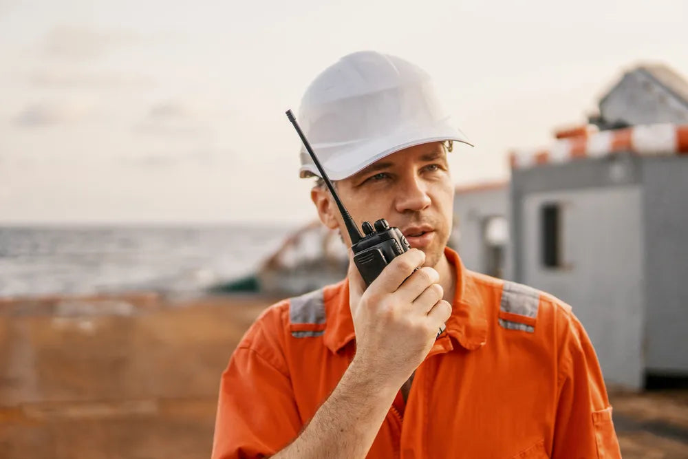 Fotografía de un joven que trabaja en construcción usando uno de los radios para operaciones industriales