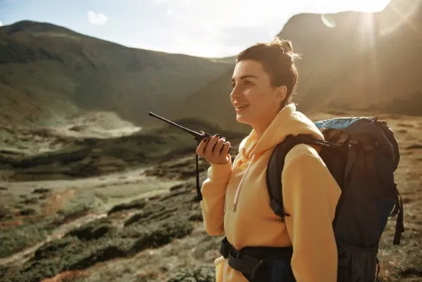 Fotografía a una mujer en un valle comprobando cuánto alcance tiene un radio de comunicación de COMREGIO