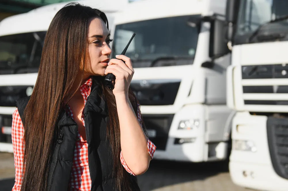 Foto de una mujer transportista que usa uno de los radios para comunicación interna empresarial